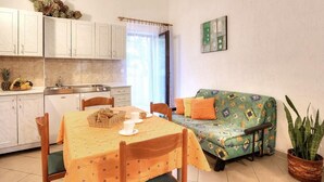 A cozy living room with a dining table, chairs, a sofa, and a potted plant. - Grozdana Nr.1A by Interhome (Krk/Baška)