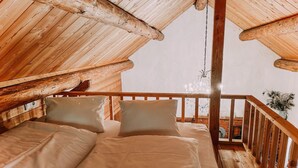 Une chambre confortable avec un plafond en bois et un balcon.