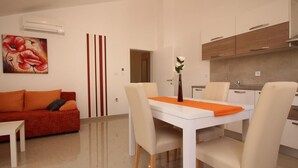 A modern living room with a dining table, sofa, and kitchen area. - Gorica II A2+1 br.9 by Interhome (Krk/Baška)