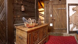 Um quarto rústico de madeira com um armário de madeira, um tapete vermelho estampado e uma porta de madeira com uma tranca de metal.