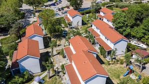 A residential area with multiple houses featuring red-tiled roofs, surrounded by greenery and a parking lot. - Corinthia 4 by Interhome (Krk/Baška)
