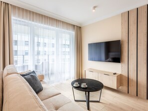A modern living room with a sofa, a round coffee table, and a flat-screen TV mounted on the wall. - in den Sun Towers am Meer by Interhome (Swinoujscie)