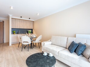 A modern living room with a sofa, a coffee table, and a dining area with chairs and a table. - in den Sun Towers am Meer by Interhome (Swinoujscie)
