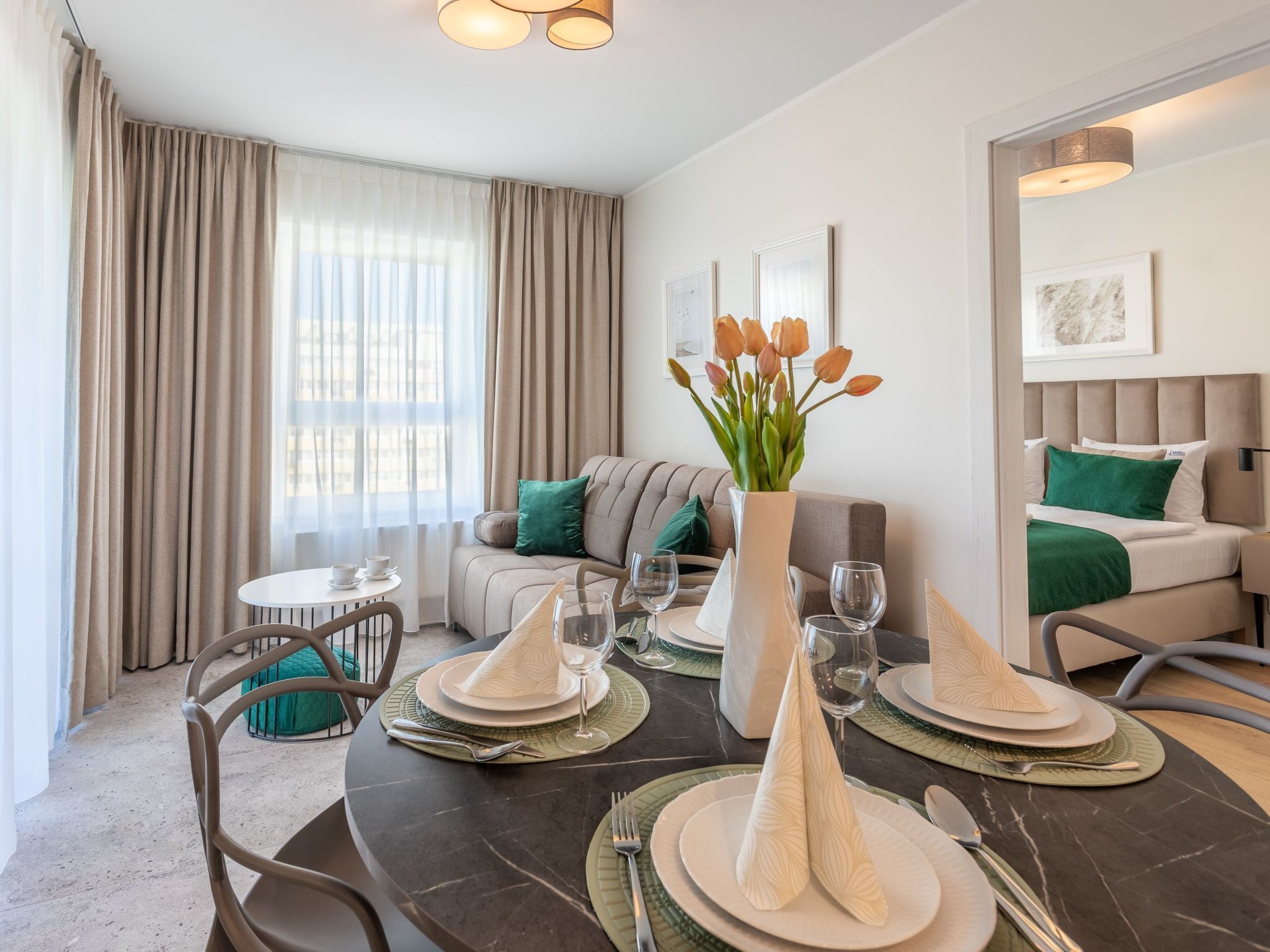 A modern hotel room with a dining area, a sofa, and a bed.