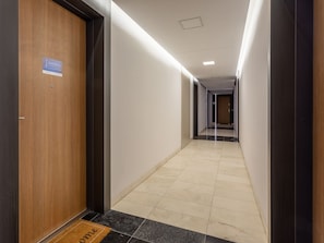 A hallway with a wooden door on the left, a sign above it, and a doormat at the entrance. The hallway is well-lit with overhead lights and has a tiled floor. - Gemütliche, helle Ferienwohnung an der Ostsee by Interhome (Swinoujscie)