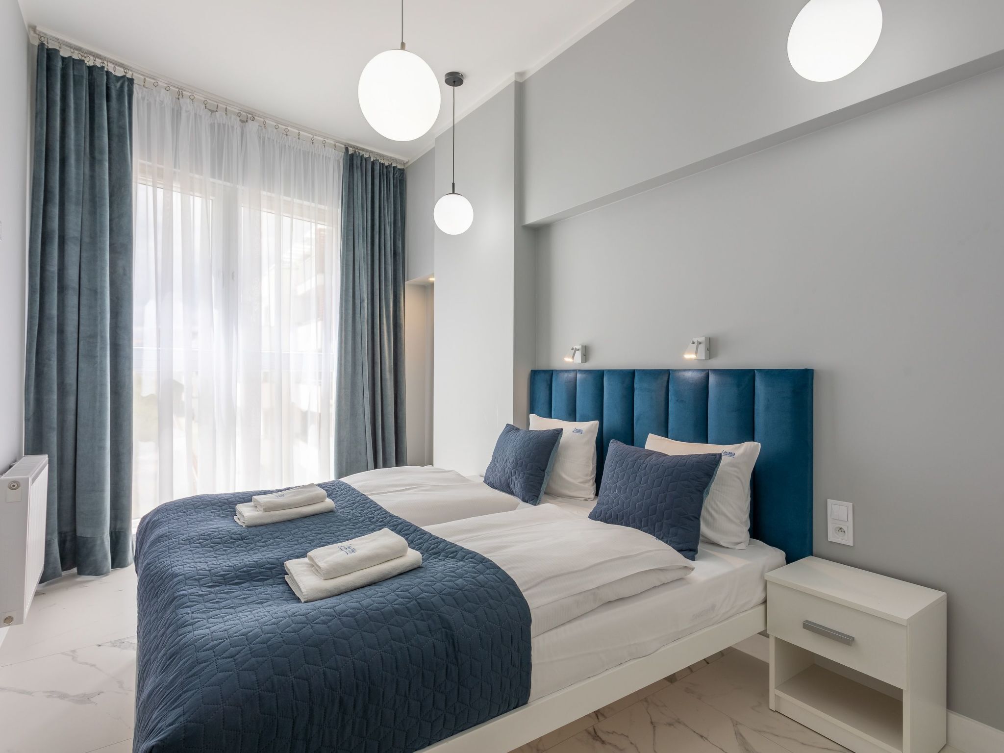 Een moderne slaapkamer met een groot bed, twee nachtkastjes en een bedtafel.