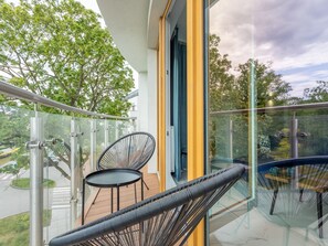 A balcony with glass railings, a wicker chair, and a small table. - Tower 27 - Ihre Ferienwohnung am Meer by Interhome (Swinoujscie)