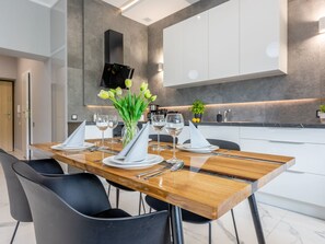 A modern dining area with a wooden table set for four, black chairs, and a vase of flowers. - Tower 27 - Ihre Ferienwohnung am Meer by Interhome (Swinoujscie)