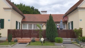 Ein zweistöckiges Gebäude mit rotem Ziegeldach, Holzzaun und Hinweisschildern mit Zimmernummern.
