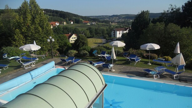 Ein Schwimmbecken mit Wasserrutsche, Liegest ühlen und Sonnenschirmen.