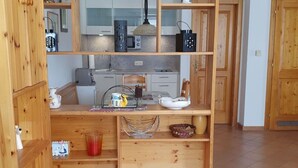 Eine kompakte Küche mit Holzschränken, einer Mittelinsel und Fliesenboden.