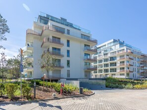 A modern multi-story residential building with balconies, a landscaped garden area, and a clear sky. - Topmoderne Ferienwohnung Albus 419 by Interhome (Swinoujscie)
