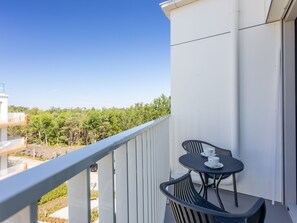 A balcony with a table and chairs, overlooking a forested area. - Topmoderne Ferienwohnung Albus 419 by Interhome (Swinoujscie)