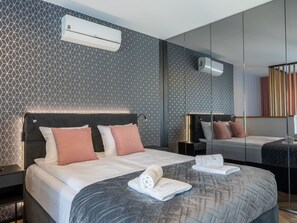 A modern hotel room with a geometric patterned wall, a large bed with a dark headboard, and a mirror reflecting the room. - Topmoderne Ferienwohnung Albus 419 by Interhome (Swinoujscie)