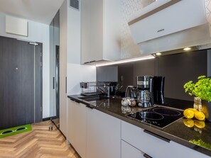 Una cucina moderna con un piano di lavoro nero, una macchina da caffè e una piccola pianta con limoni.