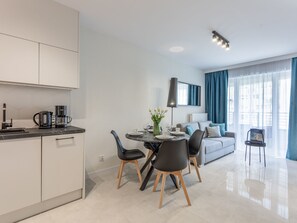 A modern kitchen with white cabinets, a black coffee maker, and a dining area with a round table, chairs, and a vase of tulips. - Elegante Ferienwohnung an der Ostsee by Interhome (Swinoujscie)