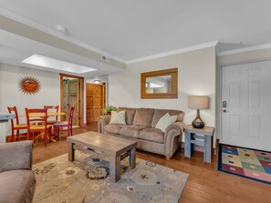Ein Wohnzimmer mit einer Couch, einem Couchtisch und Sesseln. Eine Holztür und ein Spiegel befinden sich an der Wand.