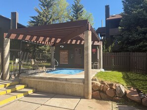 A covered outdoor pool area with a pergola, a spa pool sign, and a stone wall. - Cozy 2-bedroom condo with Fireplace in a perfect Park City location/Olympic Park (Park City)