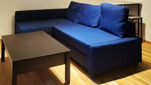 A modern living room with a blue sofa, a small table, and a ceiling light fixture. - Graz Green Studio by Interhome (Graz)