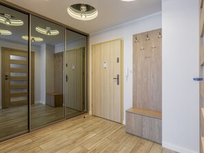 A modern room with wooden flooring, a sliding glass door, a wooden wardrobe with hooks, and a bench. - Ostsee-Ferienwohnung Bianco 8 mit Kamin by Interhome (Swinoujscie)