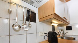 Ett modernt kök med en gasspis, en kaffebryggare och köksredskap som hänger på väggen.