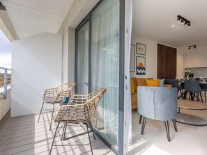 Ein moderner Wohnraum mit Balkon, Essbereich und Küche.