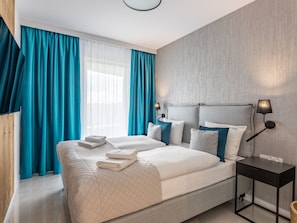 Ein modernes Hotelzimmer mit einem großen Bett, einem Nachttisch und einem Beistelltisch.