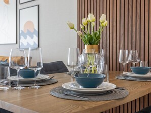 Ein Esstisch, gedeckt mit blauen Schalen, Weingläsern und einer Vase mit Tulpen.