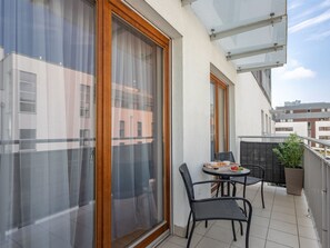 A balcony with a table and chairs, a potted plant, and a view of buildings. - Ferienappartement Platan 1 auf Usedom by Interhome (Swinoujscie)