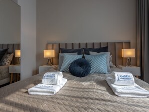 A neatly made bed with two folded towels, a headboard, and bedside lamps. - Ferienappartement Platan 1 auf Usedom by Interhome (Swinoujscie)