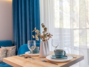 A dining table with a vase of dried flowers, two wine glasses, and a blue ceramic cup on a wooden table. - Dune 736 by Interhome (Swinoujscie)