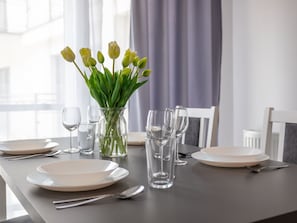 Ein Esstisch, gedeckt mit Tellern, Besteck und einer Tulpenvase.