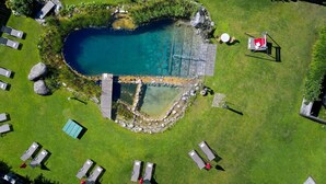 An aerial view of a swimming pool surrounded by a grassy area with lounge chairs and a small deck. - Eck-Haus Nr. 800 by Interhome (Neukirchen am Großvenediger)