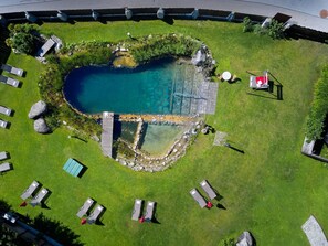 Luftaufnahme eines Swimmingpools, umgeben von einer Rasenfläche mit Liegestühlen und einer kleinen Terrasse.