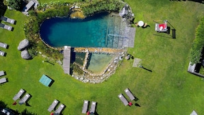 An aerial view of a swimming pool surrounded by a grassy area with lounge chairs and a small deck. - Wohnung Biohaus in Neukirchen am Großvenediger by Interhome (Neukirchen am Großvenediger)