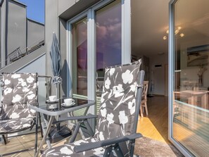 A modern outdoor seating area with a glass table and chairs, a staircase, and a view of the interior. - Helle Ferienwohnung Bianco 49 by Interhome (Swinoujscie)
