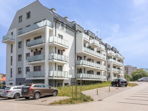A multi-story residential building with balconies, parked cars, and a clear sky. - Helle Ferienwohnung Bianco 49 by Interhome (Swinoujscie)