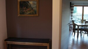 Ett rum med en träbänk, en tavla på väggen och en matplats med stolar och ett bord.