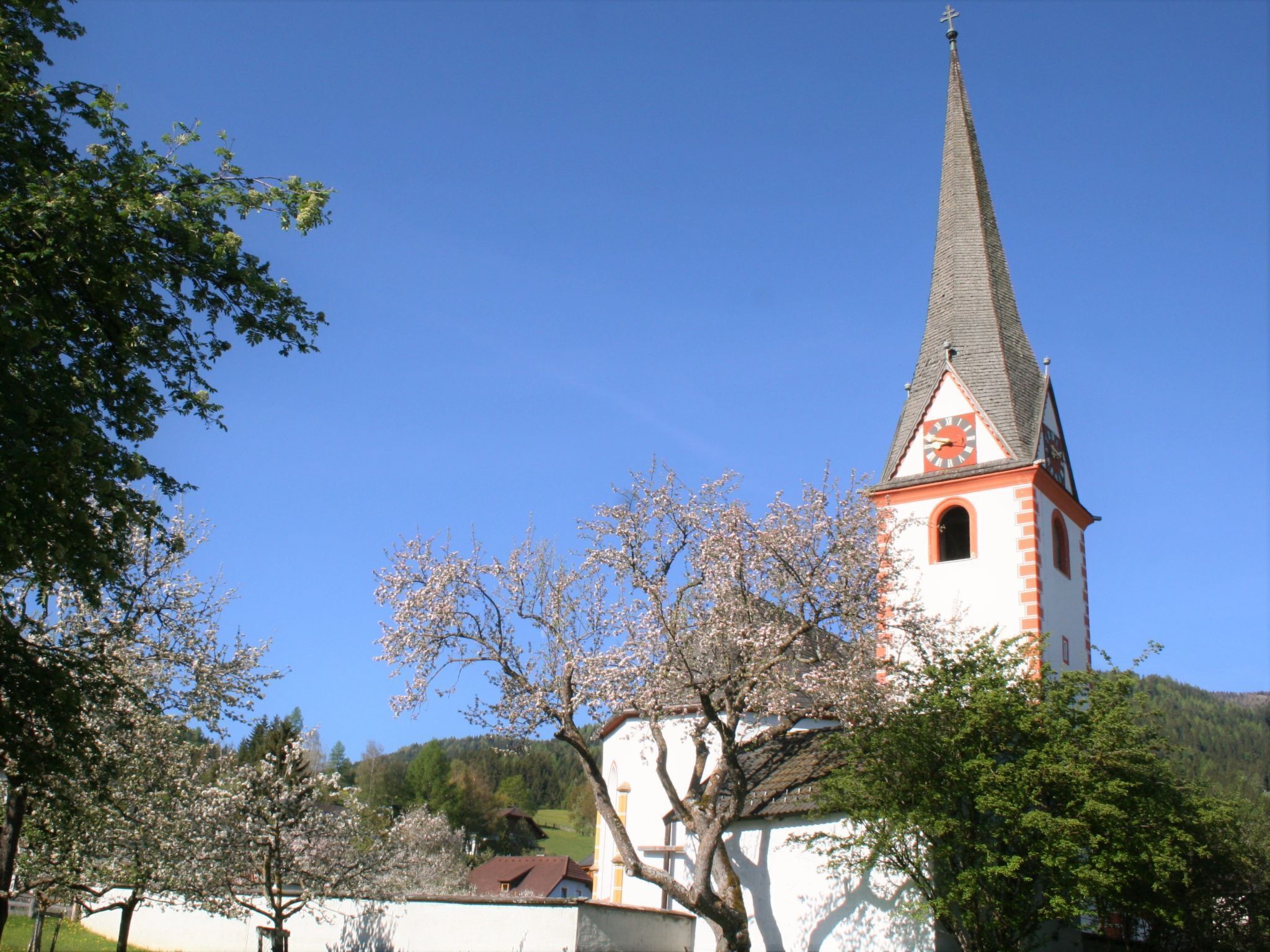Eine Kirche mit einem hohen Kirchturm und einer Uhr an der Seite.
