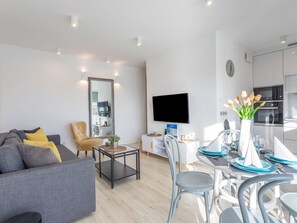 A modern living room with a grey sofa, yellow cushions, a coffee table, and a TV mounted on the wall. - Geräumiges Ferienappartement Bianco 31 by Interhome (Swinoujscie)
