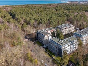 Ein Wohnkomplex mit mehreren Mehrfamilienhäusern, umgeben von dichtem Wald in Küstenähe.