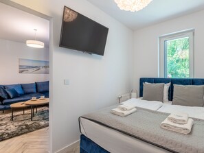 A modern hotel room with a bed, a sofa, a TV, and a window with a view of greenery. - Matejki 5 am Yachthafen von Usedom by Interhome (Swinoujscie)