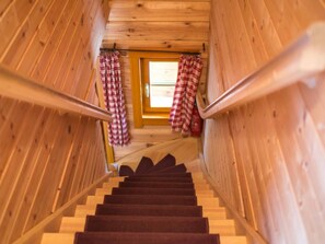 A wooden staircase with a carpeted handrail, leading to a door with checkered curtains. - Tschaneck by Interhome (Sankt Margarethen im Lungau)