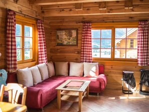 A cozy cabin interior with a wooden interior, a sofa, a table, and a window with curtains. - Tschaneck by Interhome (Sankt Margarethen im Lungau)