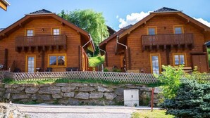 Eine Holzhütte mit Steineingang, einem Balkon und einer kleinen Sitzgelegenheit im Freien.