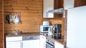 Eine kleine Küche mit Holzwänden, Backofen, Mikrowelle, Kaffeemaschine und Spüle.
