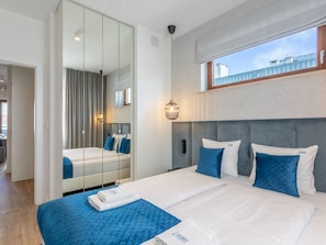 Ein modernes Hotelzimmer mit einem großen Bett, einem Spiegel und Blick auf die Stadt.