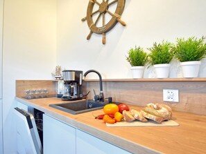 A kitchen with a wooden countertop, a coffee maker, a sink, and a ship's wheel decoration. - Sand Rose am Yachthafen by Interhome (Swinoujscie)