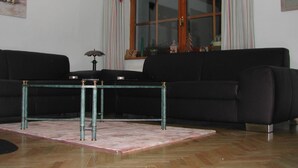 A living room with a black sofa, a glass coffee table, and a striped curtain. - Gemütliches Ferienhaus in Lofer mit Garten by Interhome (Lofer)