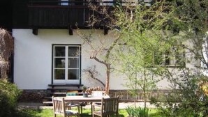 A white building with a dark roof, a window, and a small porch area. - Gemütliches Ferienhaus in Lofer mit Garten by Interhome (Lofer)